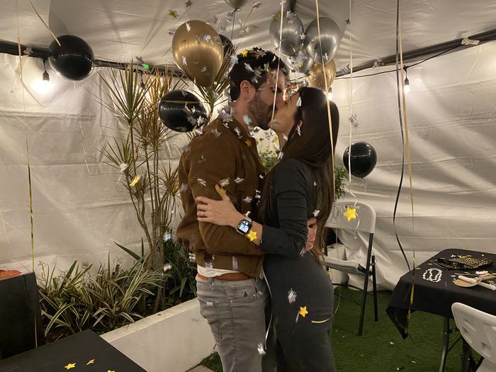 Un beso en una fiesta, entre globos y luces